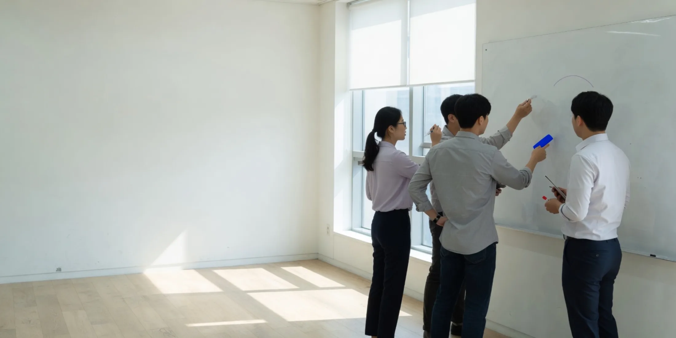 밝은 오피스 창가에서 화이트보드를 두고 논의하는 팀