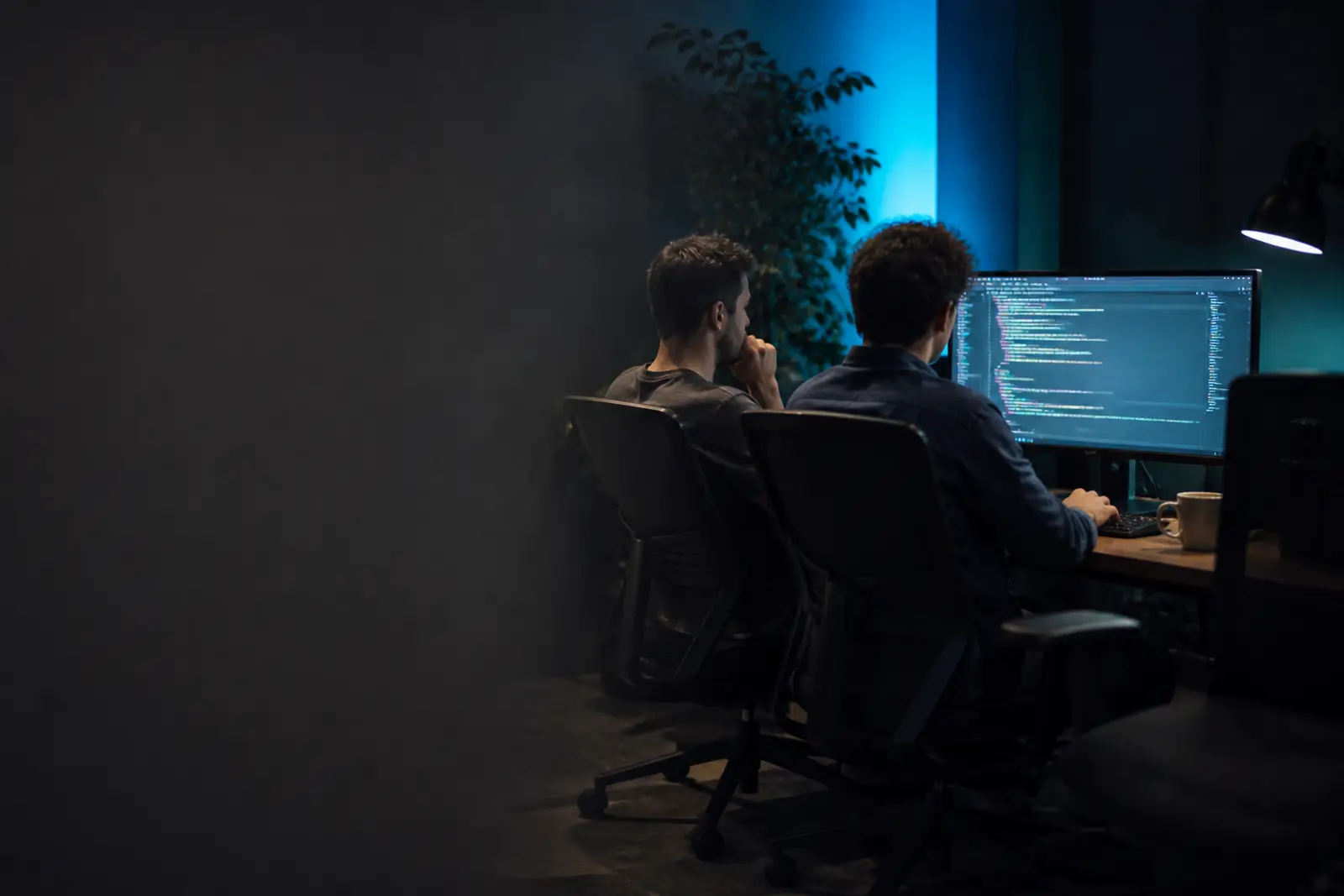 Two developers walking back through code on one screen